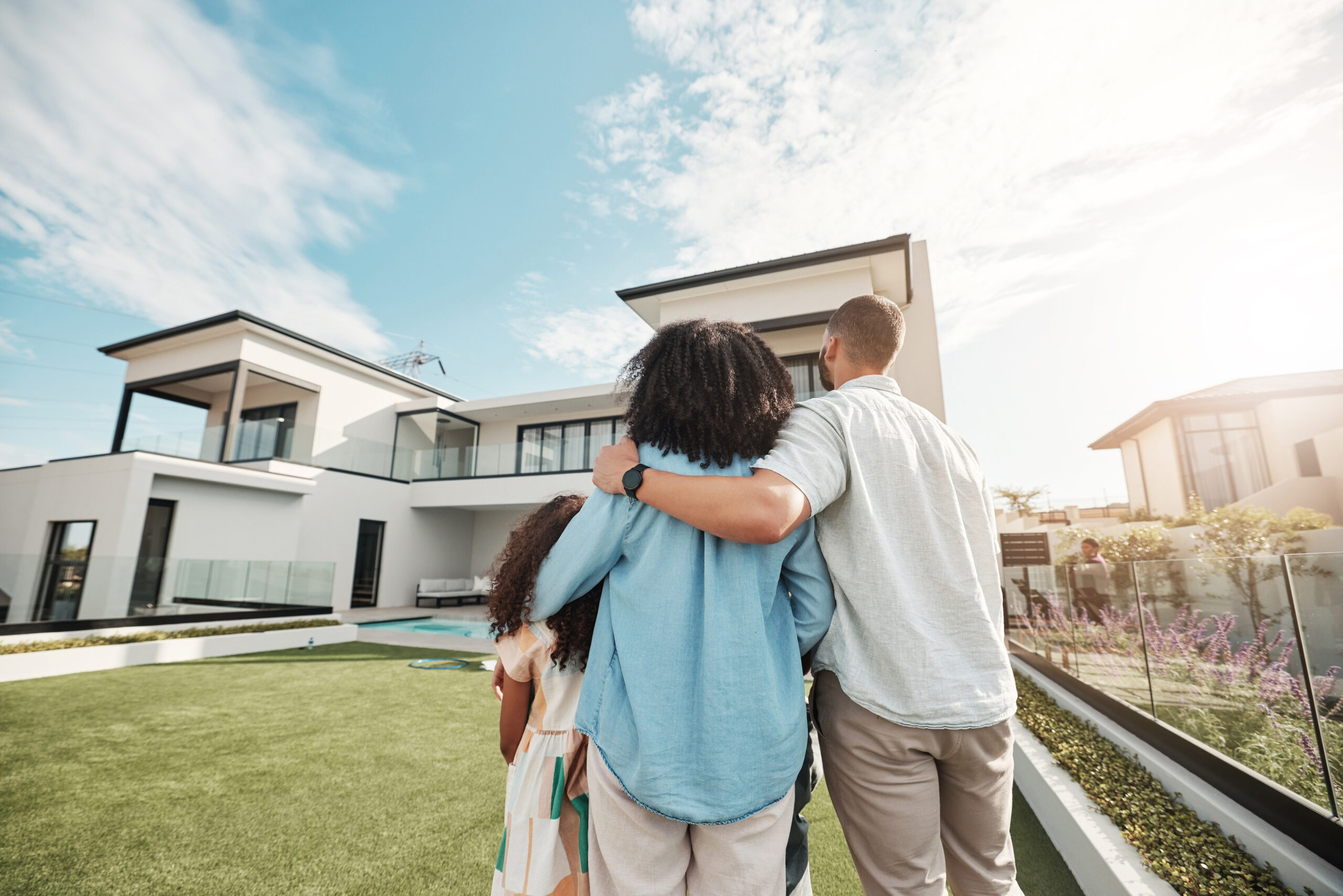 Love, new home and family standing in their backyard looking at their property or luxury real estate. Embrace, mortgage and parents with their children on grass at their house or mansion in Canada